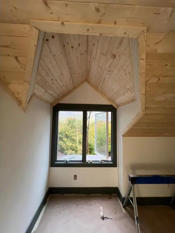Custom tongue-and-groove dormer ceiling framing a mountain-view window