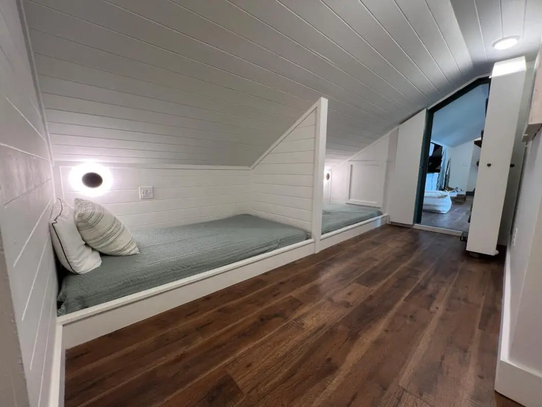 Finished attic bunk room with shiplap walls and hardwood floors