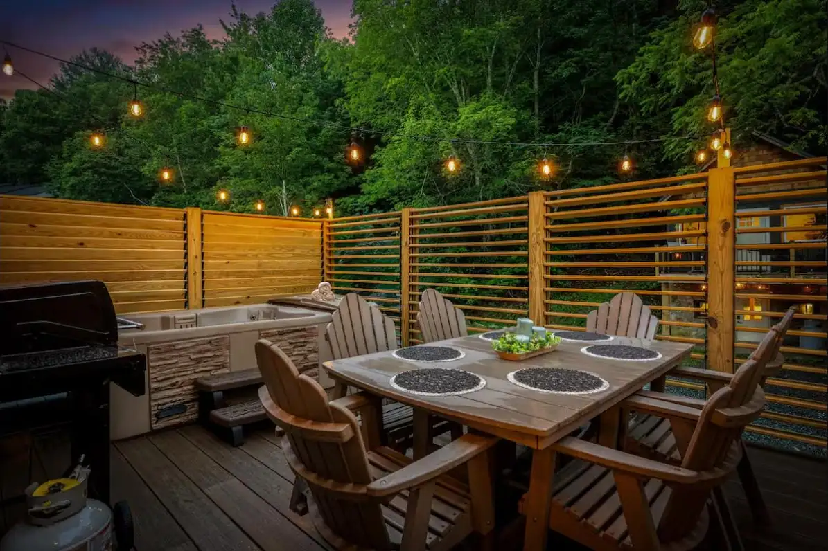 Deck dining area and hot tub wrapped in adjustable louvered privacy walls at dusk